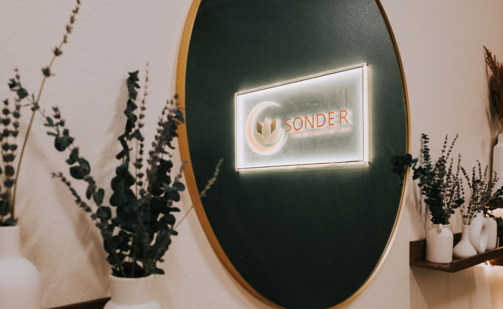 The lit Sonder sign on the green wall inside the studio